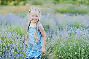 Little girl in lavender field. kids fantasy. Smiling girl sniffing flowers in summer purple lavender field