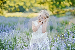 Little girl in lavender field. kids fantasy. Smiling girl sniffing flowers in summer purple lavender field