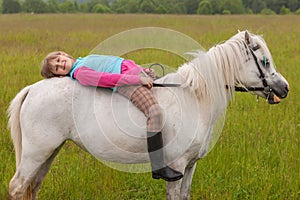 The little girl lay on her back white horse