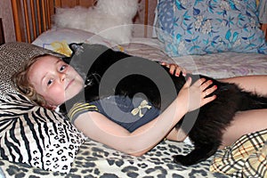 Little girl laying in bed together with her cat. Together with your pet