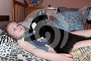 Little girl laying in bed together with her cat. Together with your pet