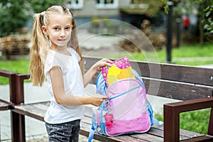 A little girl is laying books in her school backpack. The concept of school, study, education, friendship, childhood.