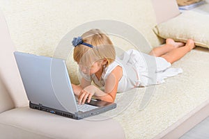 Little girl laying on the couch with laptop