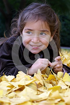 Little girl laying down over autumn leaves