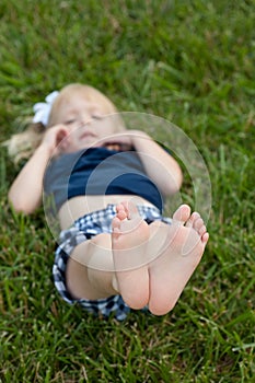 Little girl laying in the grass with feet in air