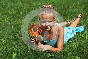 Little girl laying on the grass with a flower