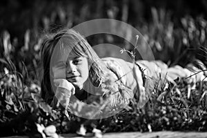 Little girl laying in grass in the park. Black and white photo.