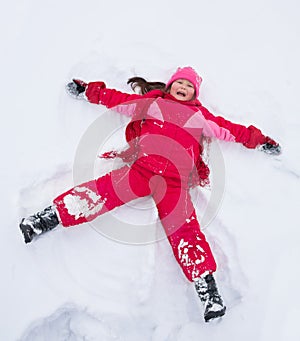 Little girl laying in star shape in snow