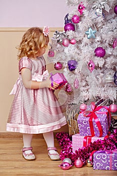 Little girl lays out the gifts under Christmas tree.