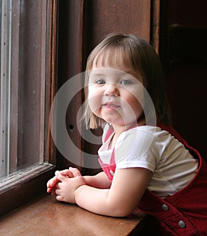 Little girl leaning on window sill photo