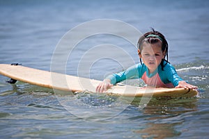 Little girl learn to surf at ocean
