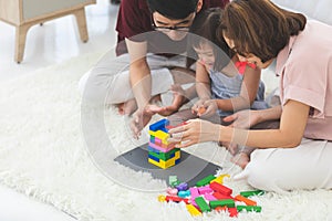 Little girl with learning disabilities Or the group of dow syndrome is learning about colorful wood toy with family teaching and