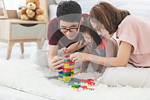 Little girl with learning disabilities Or the group of dow syndrome is learning about colorful wood toy with family teaching and photo