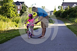Little girl learning how to ride a bike with her dad