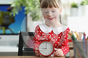 Little girl learning how to understand time and playing with red vintage clock