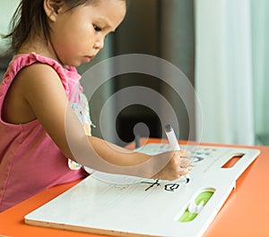 A little girl learning how to write alphabets at home. Children education
