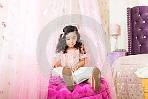 Little Girl Learning From Storybook In Bedroom