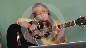 a little girl is learning to play the guitar