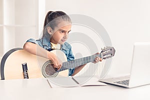 Little girl learning to play guitar online