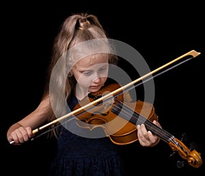 Little girl learning to play the violin isolated on black