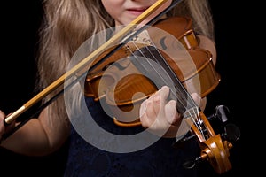 Little girl learning to play the violin isolated on black