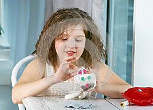 A little girl is learning to sew