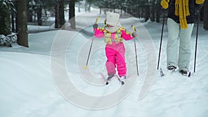 Little girl learning to skiing with mother