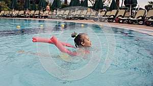 Little Girl Learning To Swim With Float And Armbands. Outdoor Pool In The Summer