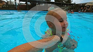 Little girl learning to swim in the pool with father