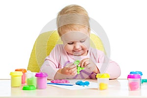 Little girl learning to use colorful play dough isolated on white background