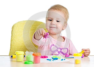 Little girl learning to use colorful play dough on white background