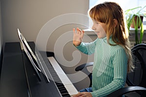 A little girl learns to play the piano from video lessons. Online distance learning during covid-19