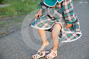 Little girl legs wearing open-toe sandals at summer. Kid in green dress