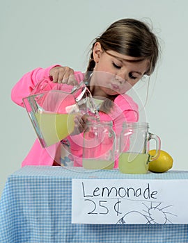 Little girl at lemonade stand pouring lemonade