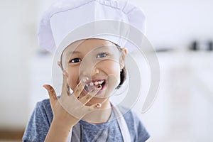 Little girl licking chocolate on her finger