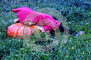 A little girl lie down on a huge pumpkin in a magical meadow. The baby is wearing a gnome costume. Magic and fireflies. Can be use