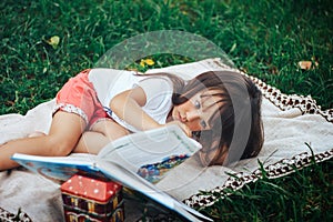 Little girl lie on grass and reading book