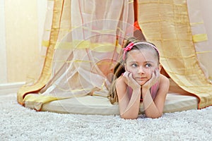 Little girl lies under baldachin photo