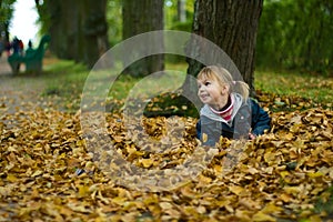 Little girl lies at yellow leaves