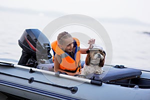 Little girl in a life jacket with her dog in a boat on the lake. Safety. summer rest