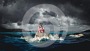 Little girl with lifebuoy sitting on a rock