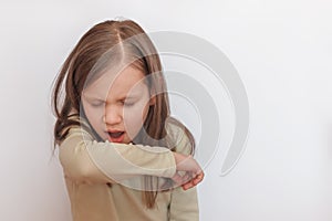 Little girl sneezes into her elbow photo