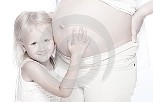 Little girl listening belly of her pregnant mother