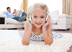 Little girl listening music lying on the floor