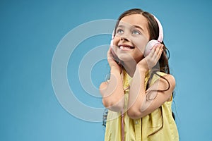 Little girl listening music in pink headphones.