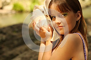 A little girl listening a seashell