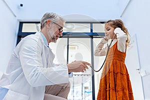 Little girl listening to the doctor's heart with stethoscope. Role reversal. Friendly relationship between the