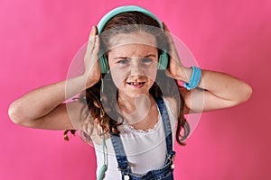 Little girl listening to music with headphones with a displeased expression