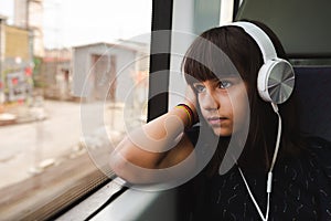 Little girl listening to music while travelling by train