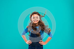 Little girl with long hair. Kid happy cute face with adorable curly hair stand over blue background. Pure beauty. Beauty